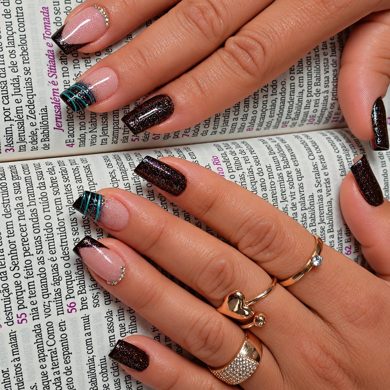 Unhas em gel com francesinha preta, glitter escuro e fios coloridos sobre uma Bíblia